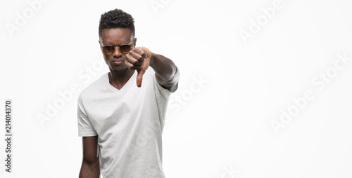 Young african american man wearing sunglasses with angry face, negative sign showing dislike with thumbs down, rejection concept