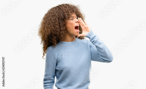 African american woman wearing a sweater shouting and screaming loud to side with hand on mouth. Communication concept. photo