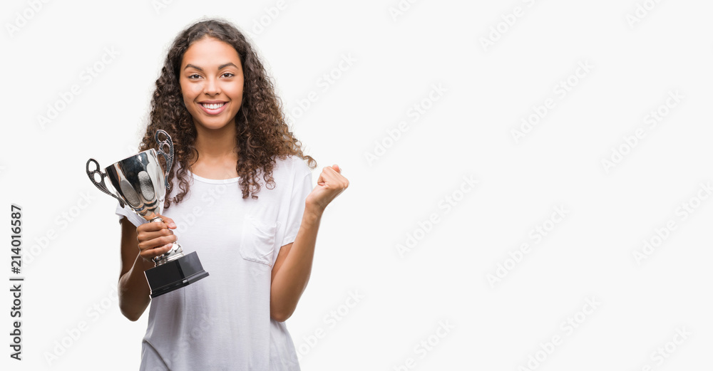 Young hispanic woman holding trophy screaming proud and celebrating victory and success very excited, cheering emotion Young hispanic woman holding trophy screaming proud and celebrating victory and success very excited, cheering emotion