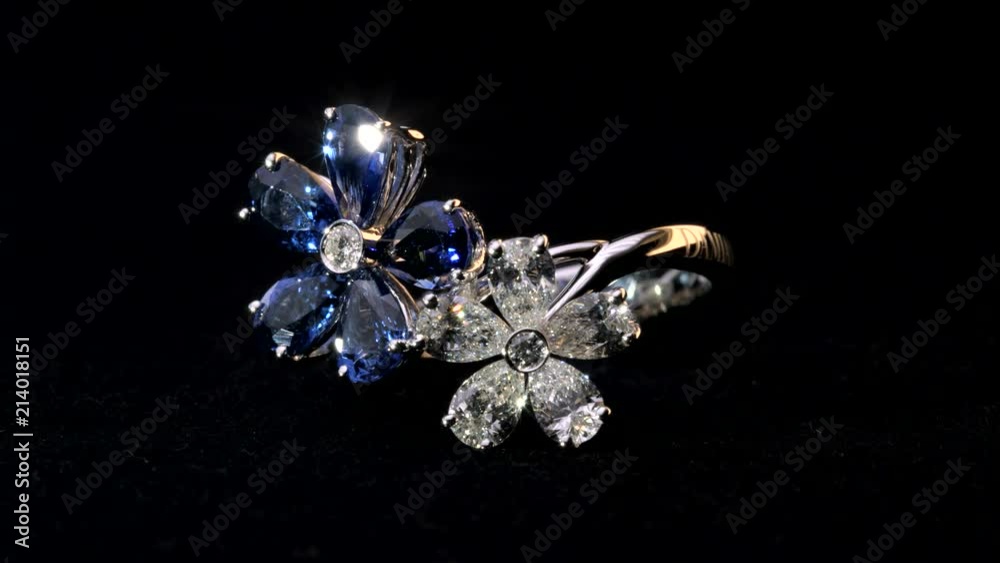 Close-up shot of two sparkling,shining white and blue flower shaped ring with diamonds and saphire jewelery. Close-up shot of two sparkling,shining white and blue flower shaped ring with diamonds and saphire jewelery.