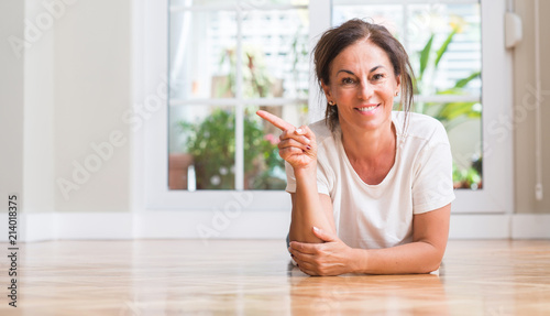 Middle aged woman very happy pointing with hand and finger to the side