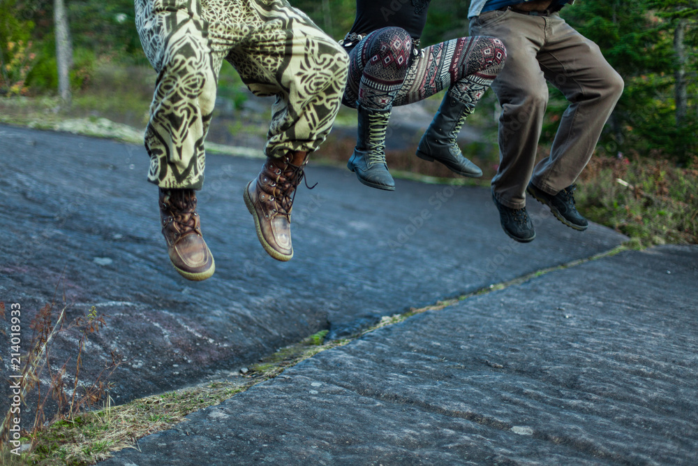 Three people jumping high in the air from a rock Three people jumping high in the air from a rock