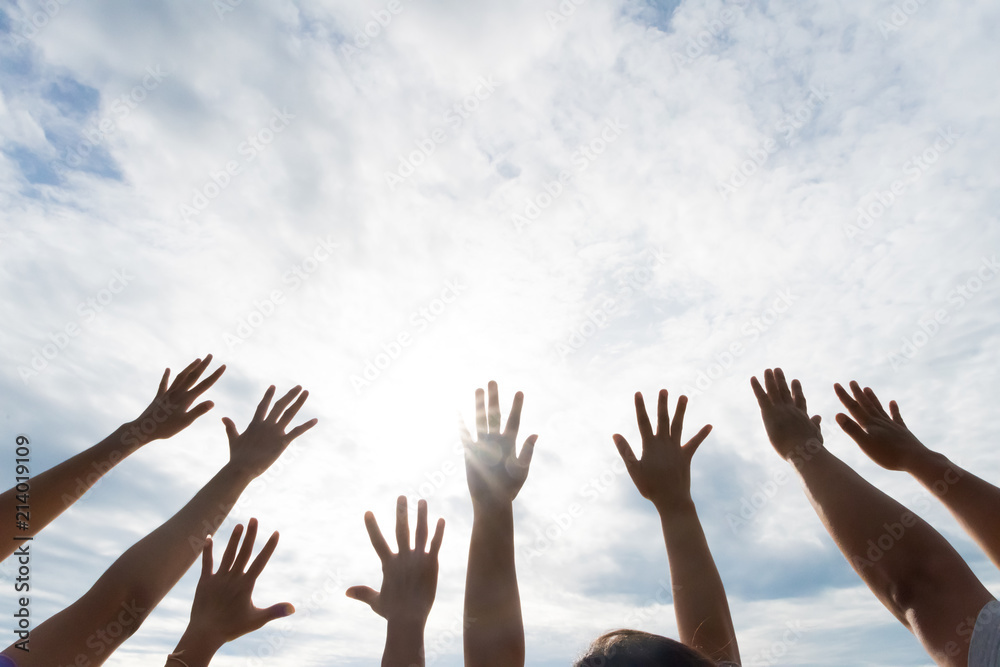 Many hands raised up against the blue sky. Friendship, Teamwork concept.