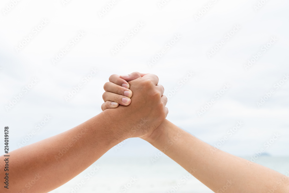 men hand shake holding together on blurred sea and sky background. Friendship Day concept. men hand shake holding together on blurred sea and sky background. Friendship Day concept.