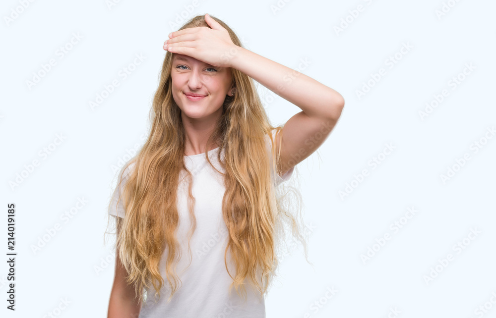 Blonde teenager woman stressed with hand on head, shocked with shame and surprise face, angry and frustrated. Fear and upset for mistake.