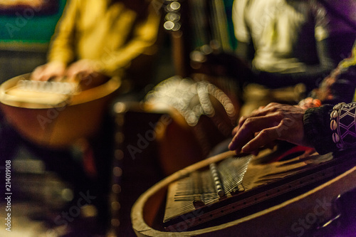 Man's hands playing kalimba with blurry musicians playing african instruments live on stage photo