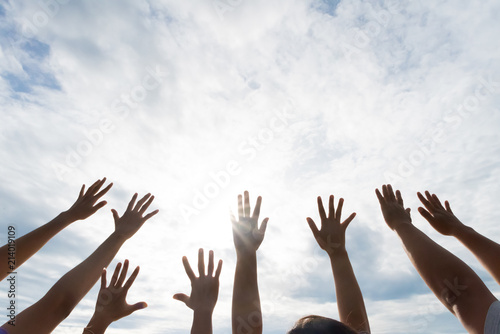 Many hands raised up against the blue sky. Friendship, Teamwork concept.