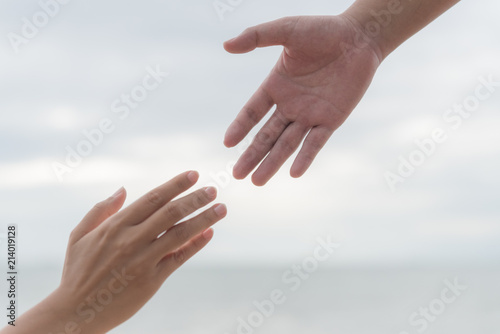 helping hands on blurred sea and sky background. Friendship Day concept. © Siam