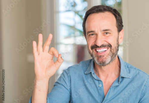 Handsome middle age man doing ok sign with fingers, excellent symbol