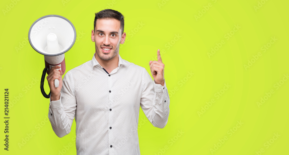 Handsome young man holding microphone surprised with an idea or question pointing finger with happy face, number one Handsome young man holding microphone surprised with an idea or question pointing finger with happy face, number one
