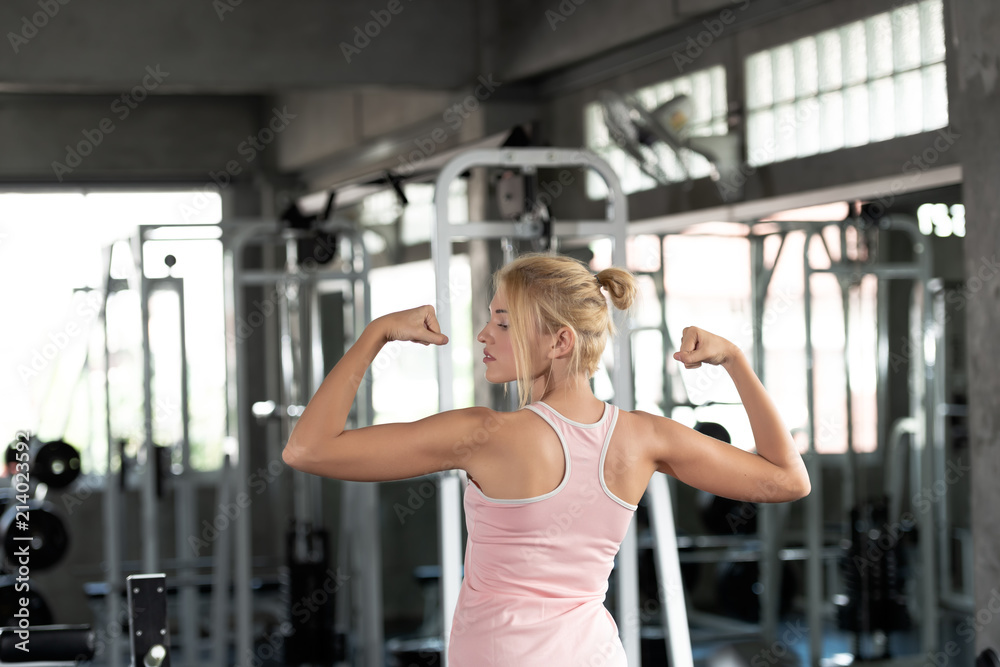 Portrait of caucasian woman happy strong is showing her muscles in the gym. Strong women concept. Portrait of caucasian woman happy strong is showing her muscles in the gym. Strong women concept.