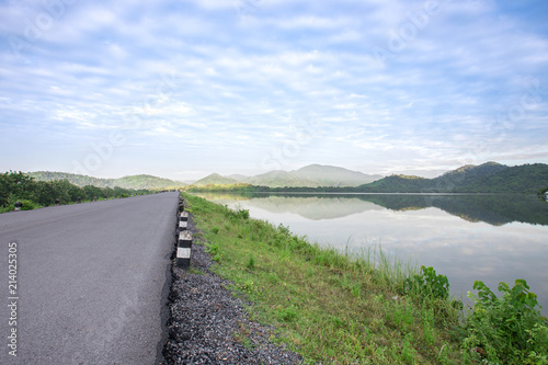 Asphalt road with reservoir on clearly blue sky and mountains.