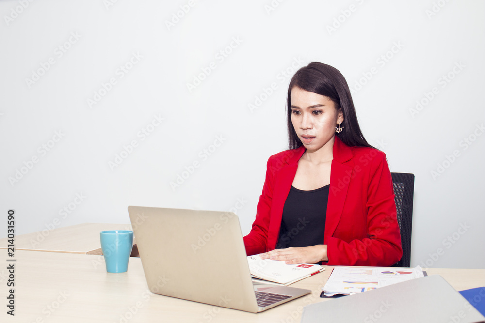 Portrait of beautiful 20-30 years.Businesswoman in red suit holding cup near laptop.She is a hard working young lady.Copy space. Portrait of beautiful 20-30 years.Businesswoman in red suit holding cup near laptop.She is a hard working young lady.Copy space.