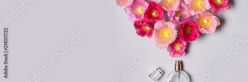 Women's perfume bottle and pink mallow flowers. Minimalism beauty concept photo