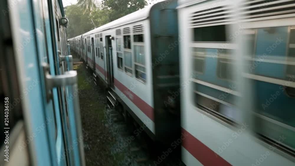 High speed train passing by, shot from another train. On board shot was filmed during sunrise on express train in Sri Lanka, in between Colombo and Ella.
