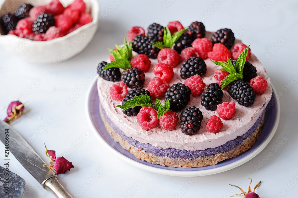 Raw vegan cake with raspberries and bluberries on white table Raw vegan cake with raspberries and bluberries on white table