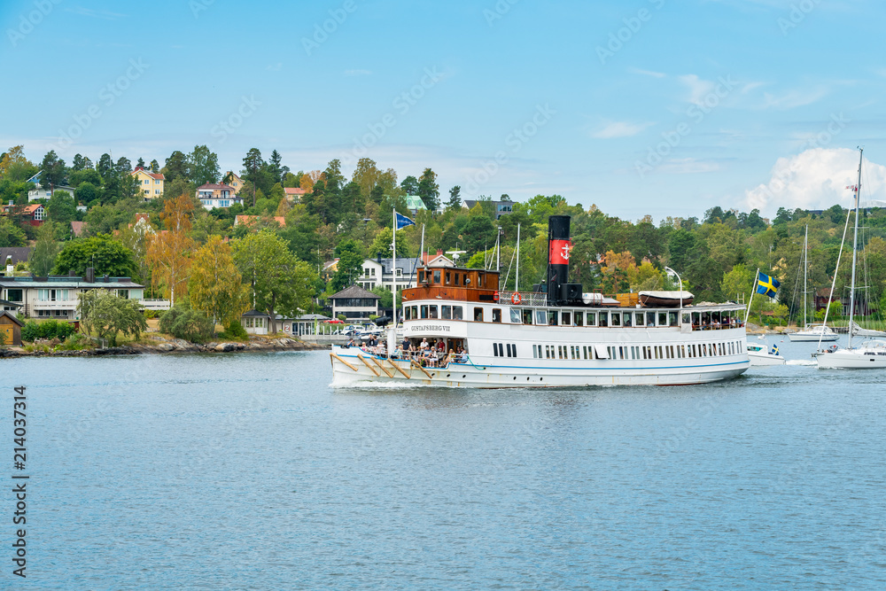 SKURUSUNDET RIVER, SWEDEN - July 11, 2018 : Sightseeing boat with tourists enjoy scenic view of both side of the rocky coast on Skurusundet river SKURUSUNDET RIVER, SWEDEN - July 11, 2018 : Sightseeing boat with tourists enjoy scenic view of both side of the rocky coast on Skurusundet river