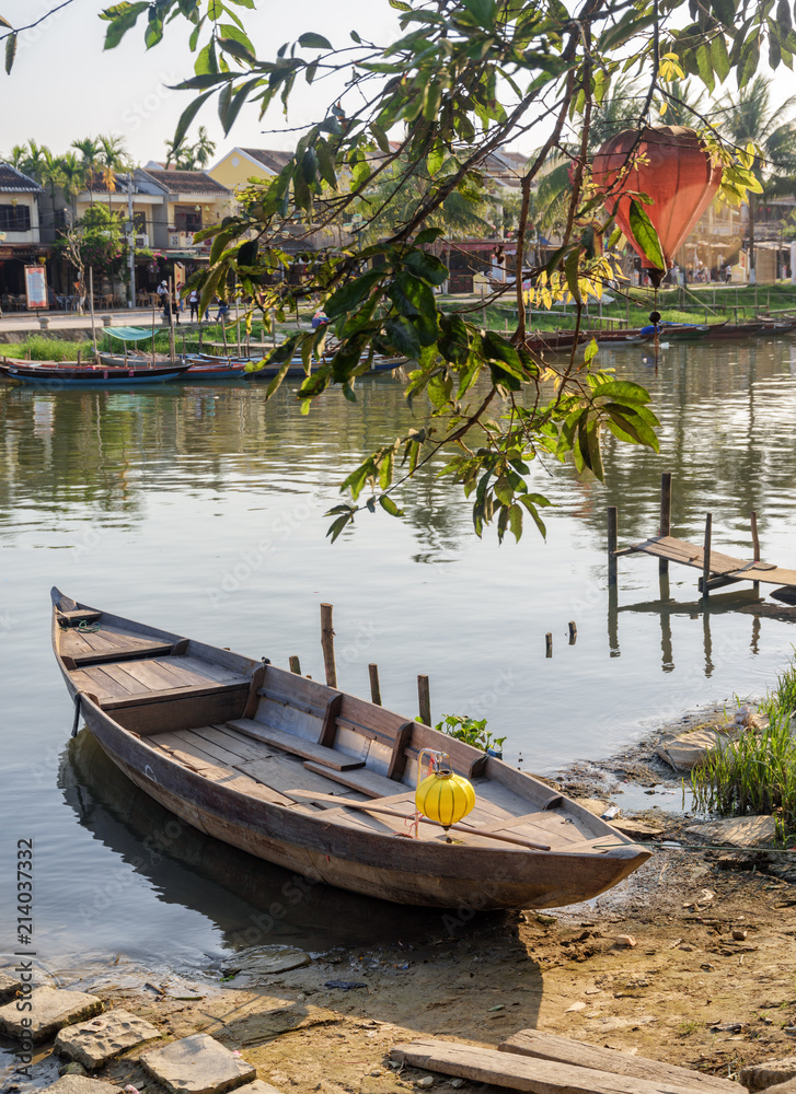 Wooden boat parked on bank of the Thu Bon River