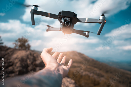 Obraz na płótnie male hand catching drone on sunset. Safe quad copter landing on the pilot's palm w salonie