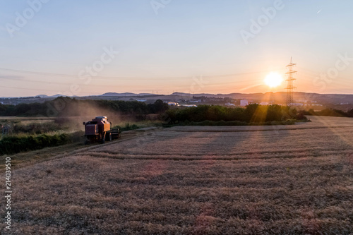 Aerial view of combine harvester harvesting an oats crop at sunset photo