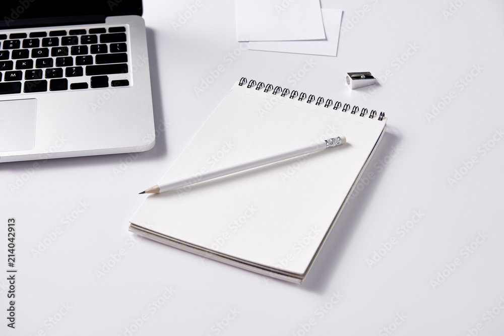 close-up shot of notebook and pencil at workplace on white surface close-up shot of notebook and pencil at workplace on white surface