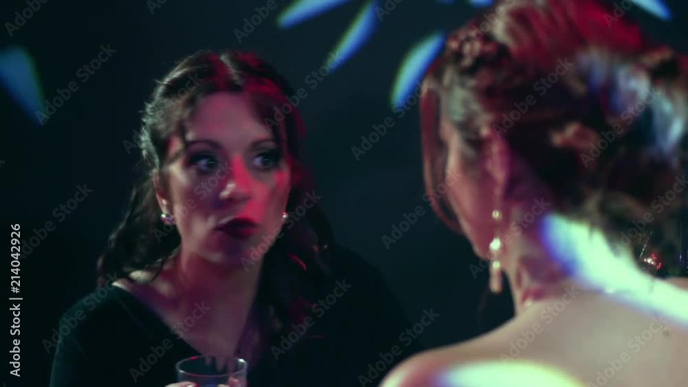 Close up of a woman arguing and complaining to a female friend in a night club while drinking wine Close up of a woman arguing and complaining to a female friend in a night club while drinking wine