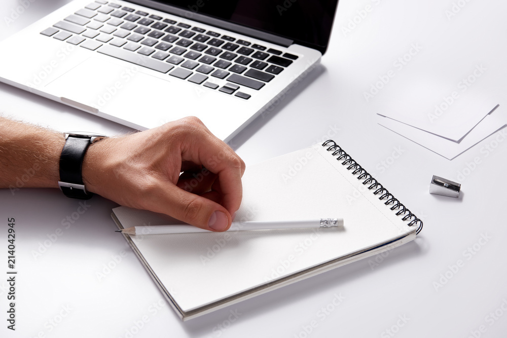 cropped shot of man with notebook and pencil lying at workplace on white surface