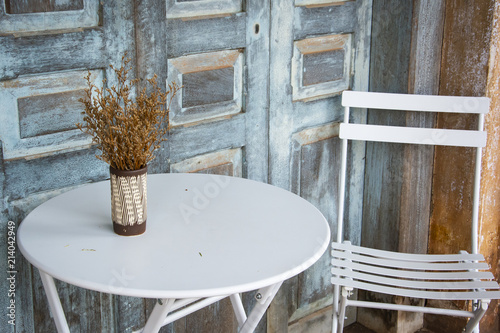 Fototapeta Naklejka Na Ścianę i Meble -  Table and chairs An open terrace in a cafe, shelf in front of wooden door and old house, selective focus, copy space