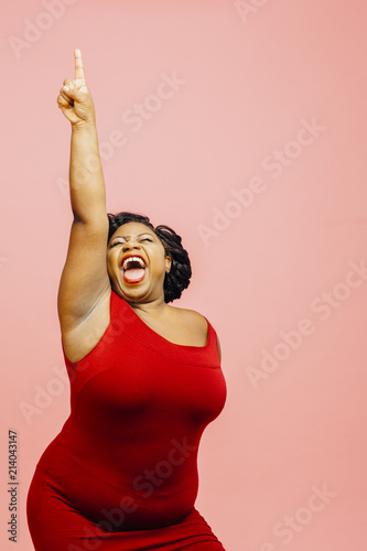 фотографія A very happy and excited woman celebrating success with arm up, mouth open and f