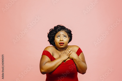 Canvas-taulu Woman holding her chest and looking up scared and uncertain, isolated on pink