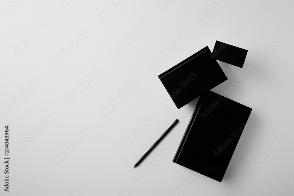 top view of black notebooks with business card and pencil on white surface for mockup top view of black notebooks with business card and pencil on white surface for mockup