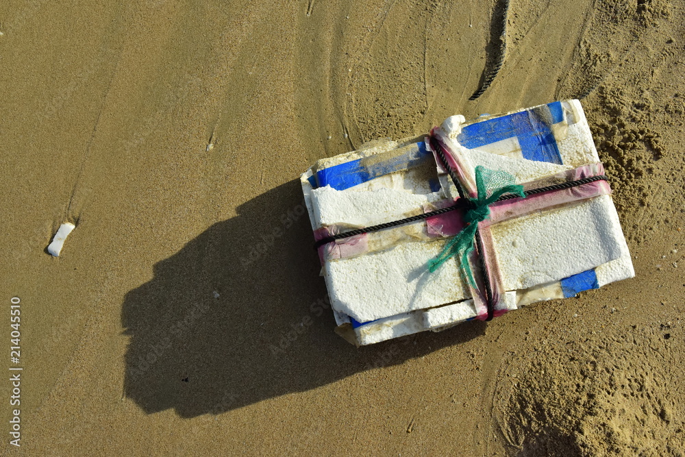 Self-made white polystyrene buoy a tied to a rope network fishing fish on a wet sand background ocean design beach fishing village. Garbage thrown ashore by waves Self-made white polystyrene buoy a tied to a rope network fishing fish on a wet sand background ocean design beach fishing village. Garbage thrown ashore by waves