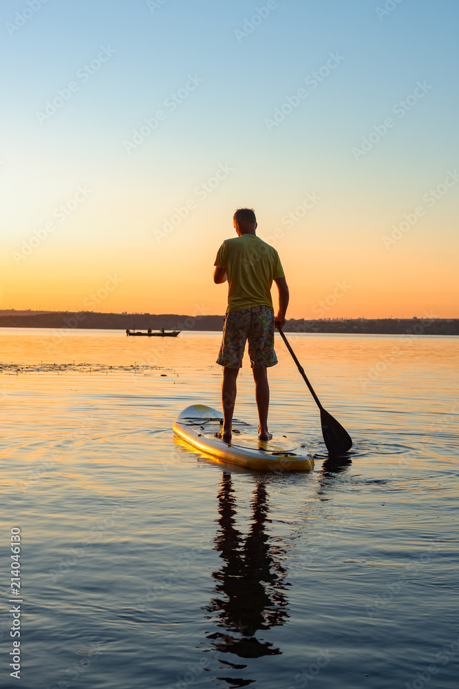 Man paddling on a SUP board during sunrise
