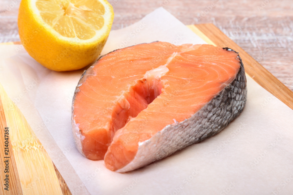 fresh raw salmon with spices and lemon on wooden cutting board. ready for cookin fresh raw salmon with spices and lemon on wooden cutting board. ready for cookin