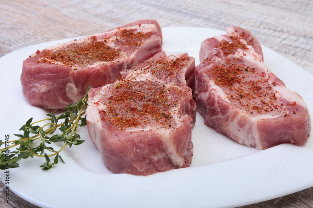 Raw pork chops, spices and rosemary on cutting board. Ready for cooking.