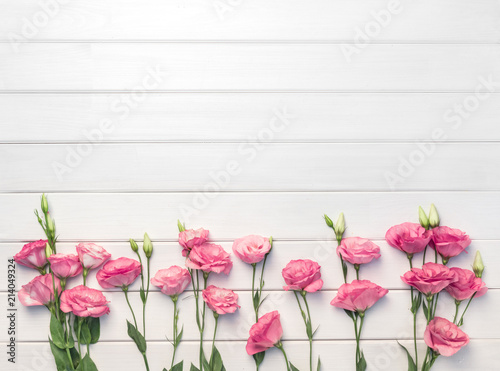 Beautiful pink eustoma flowers on white wooden background. Copy space, top view,