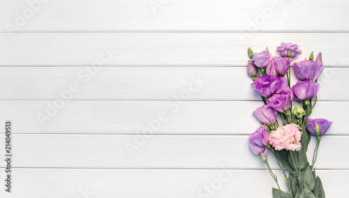Beautiful purple eustoma flowers on white wooden background. Copy space, top view,