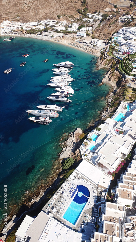Aerial drone photo of luxury speed boats docked in popular beach of Psarou with iconic resorts, Mykonos island, Cyclades