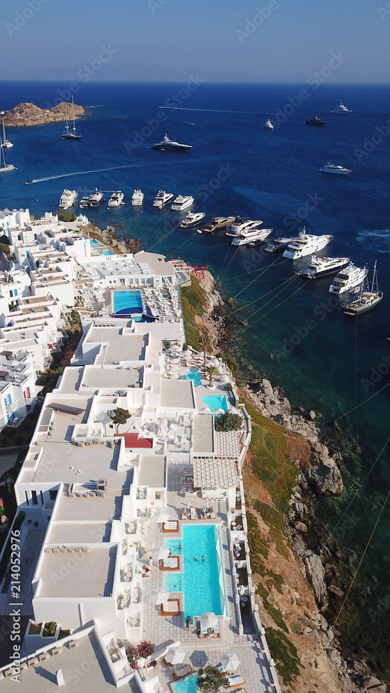 Aerial drone photo of famous pool resorts on top of rocky emerald seascape in iconic island of Mykonos, Psarou beach near Platy Gialos, Cyclades, Greece