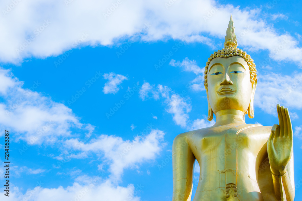 Big golden Buddha statue with blue sky background.