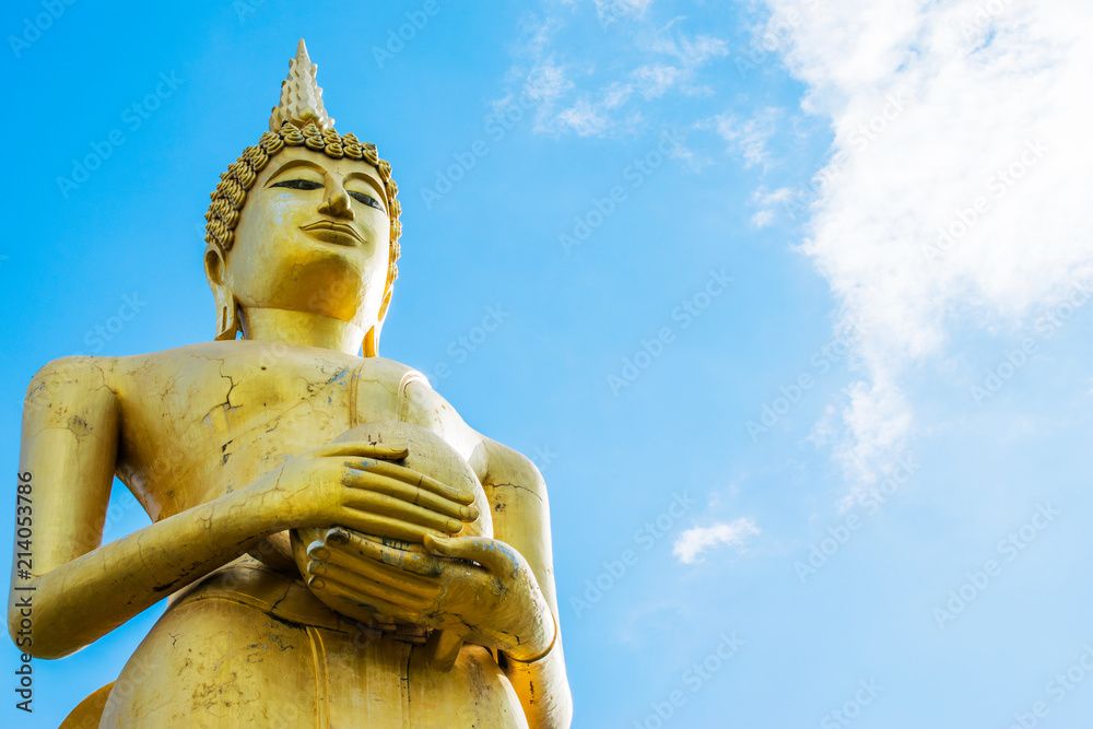 Big golden Buddha statue holding monk's alms bowl with blue sky background.