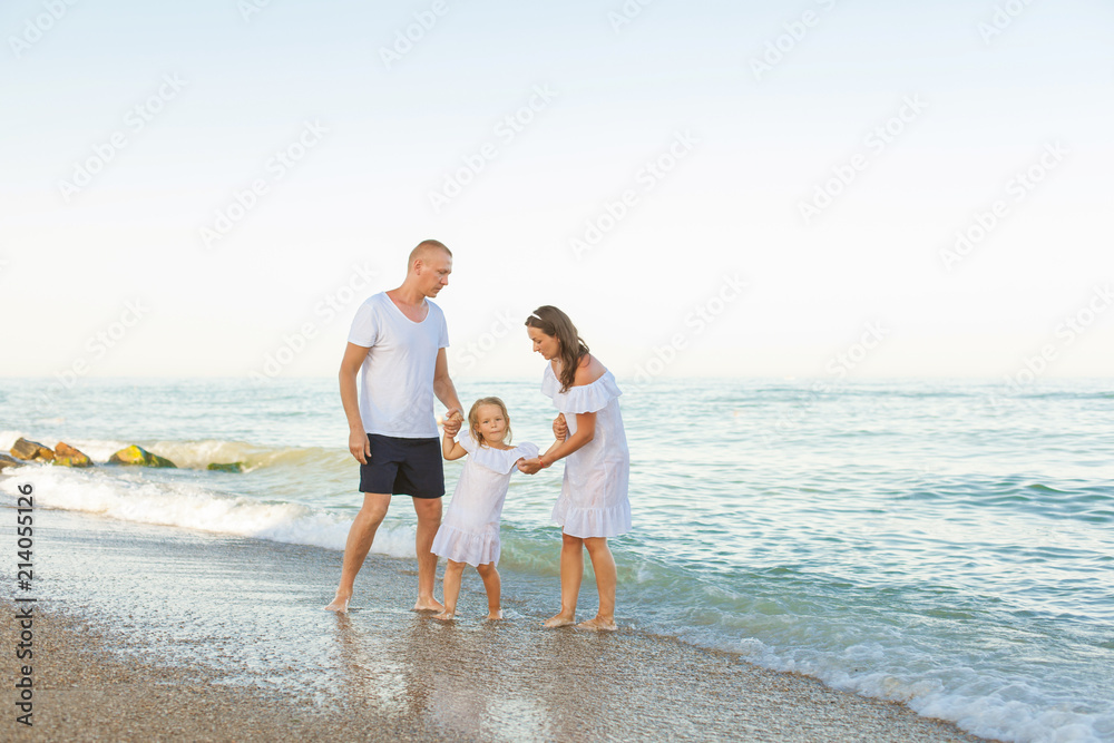 Young parents with a daughter running along the beach.