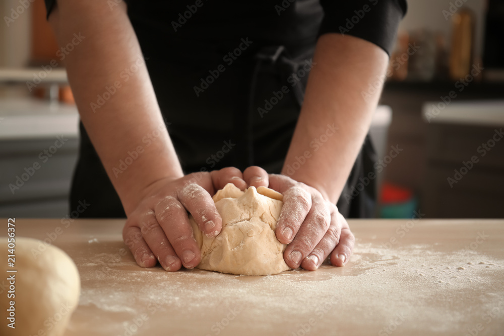 Baker kneading dough on kitchen table Baker kneading dough on kitchen table