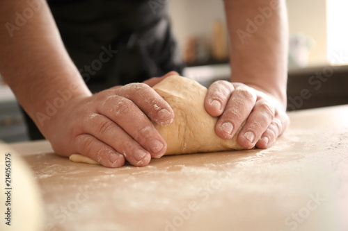 Baker kneading dough on kitchen table © Pixel-Shot