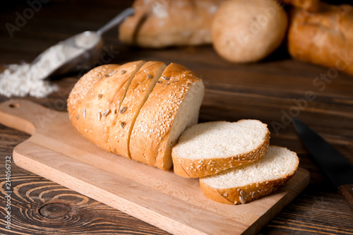 Loaf of sliced tasty bread on wooden board