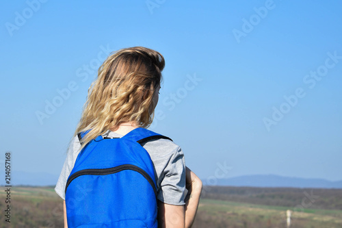 Beautiful young girl with a backpack in the mountains.