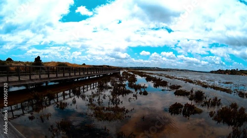 Sandy backwater with a scattering of stones and seaweed and small city on a low hills background