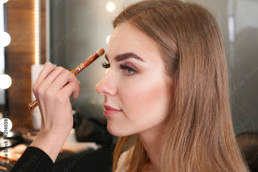 Professional makeup artist applying makeup on face of young woman in beauty salon Professional makeup artist applying makeup on face of young woman in beauty salon