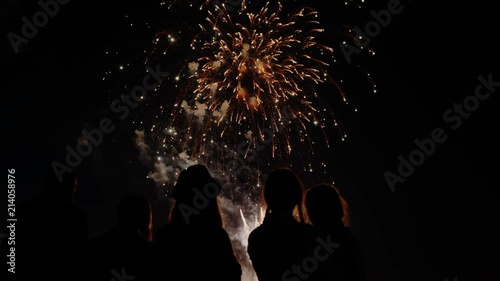 A crowd of people watch colorful fireworks and celebrate.