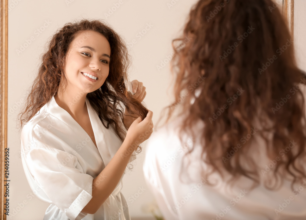 Morning of young African-American woman brushing hair near mirror Morning of young African-American woman brushing hair near mirror